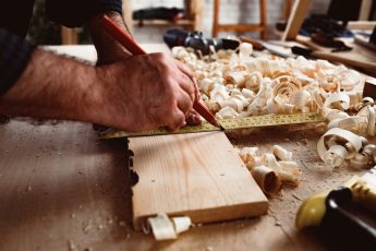 Carpenter makes pencil marks on a wood plank close up